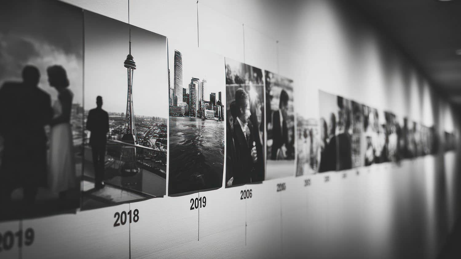 A hallway showcasing a chronological photo timeline, each picture capturing a significant moment. Black and white aesthetic.